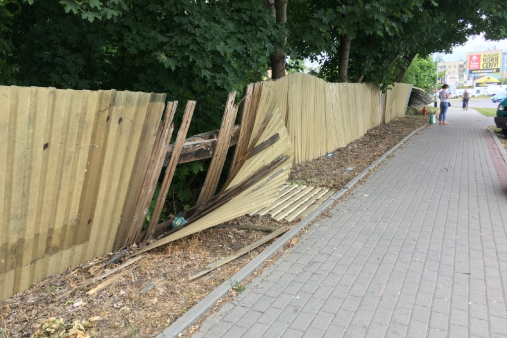 Połamany płot i obskurny baner witają przyjezdnych