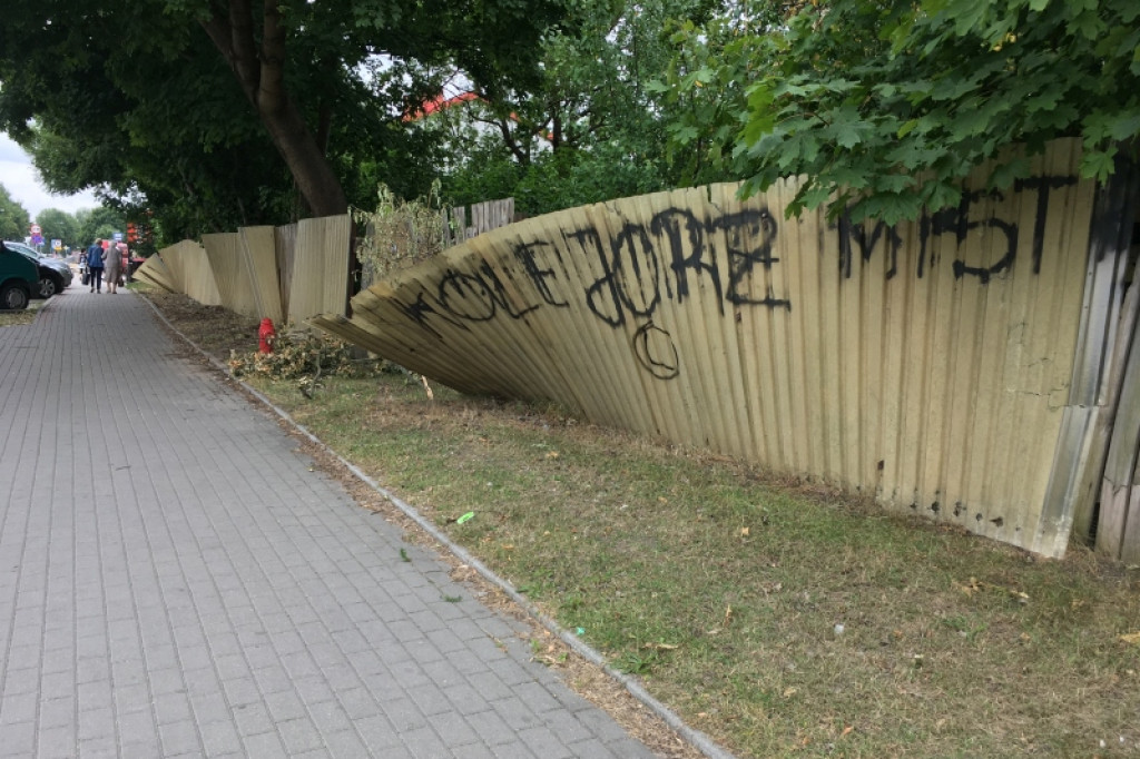 Połamany płot i obskurny baner witają przyjezdnych